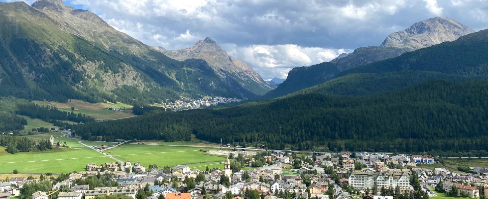 Immobilien im Engadin aus der Vogel Perspektive umringt von grünen Bergen und einer grauen Wolkendecke.